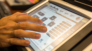 A close up of a hand working on a touch screen to monitor NMT online courses.