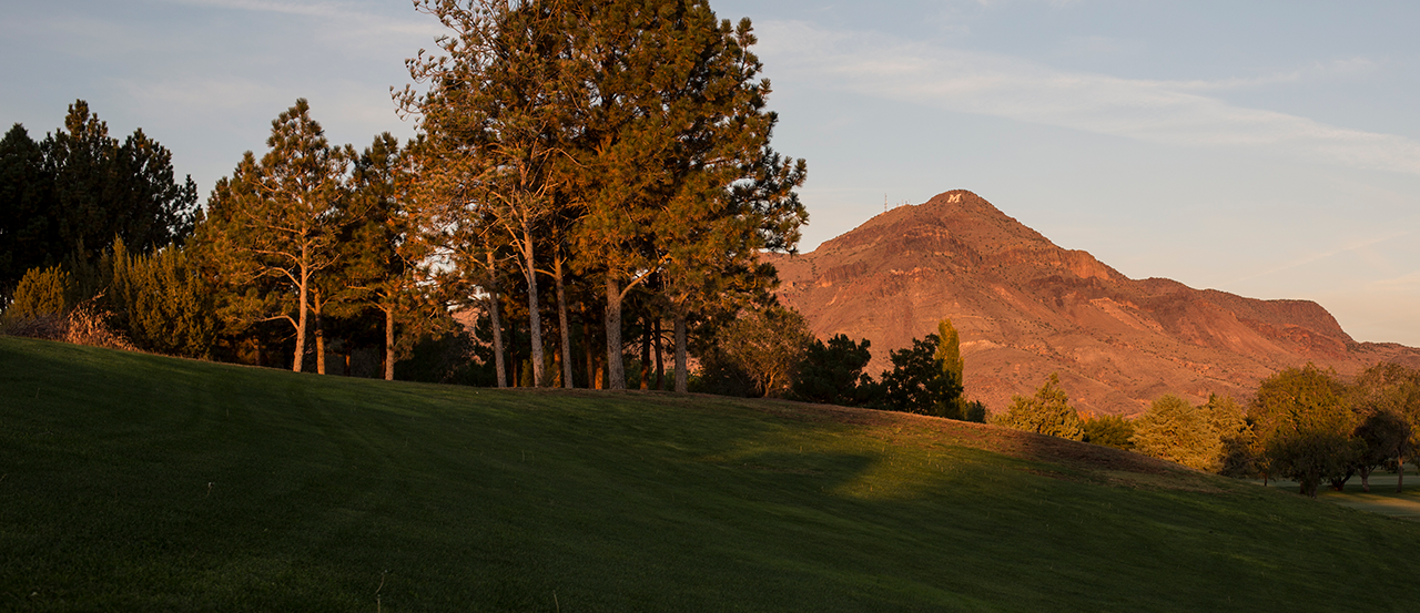 Image of M Mountain at sunrise, golf course and trees in the foreground