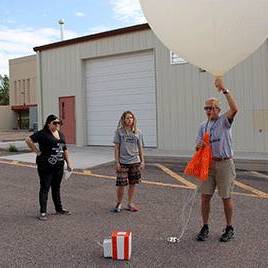 Image of Professor and Students with Balloon. 